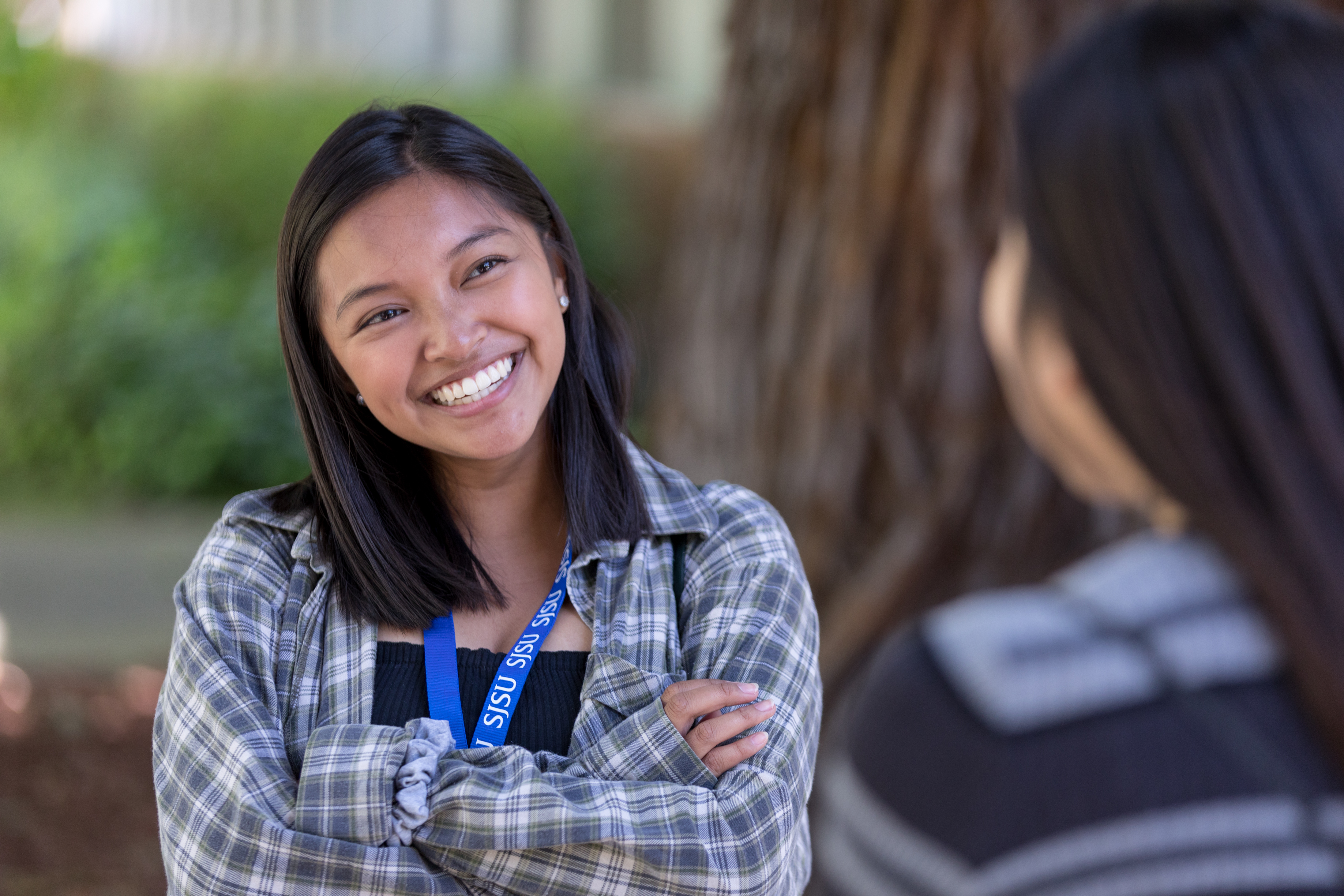 Girl outside smiling at another mid conversation 