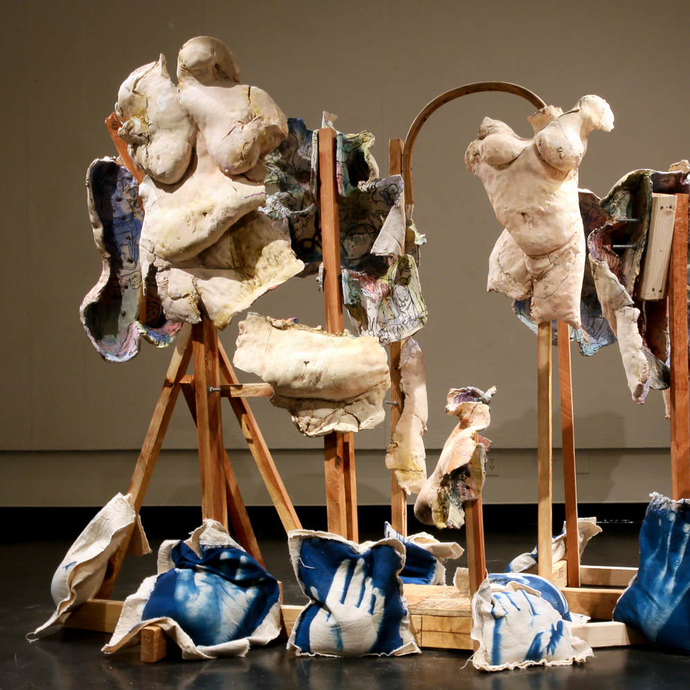 Sculptural Installation featuring clay bodies on wooden frames draped with fabric printed with images